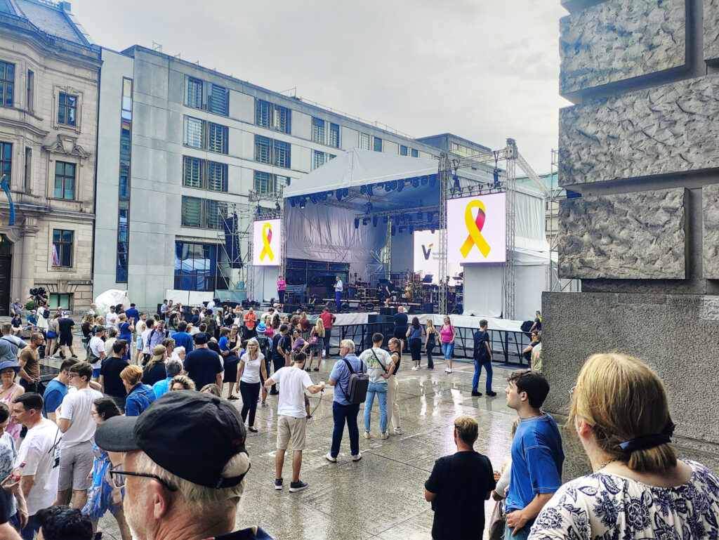 Ein Blick auf die große Bühne der Veranstlaltung. Es hat gerade einen kleinen Schauer gegeben, aber der Platz vor der Bühne ist gut besucht.